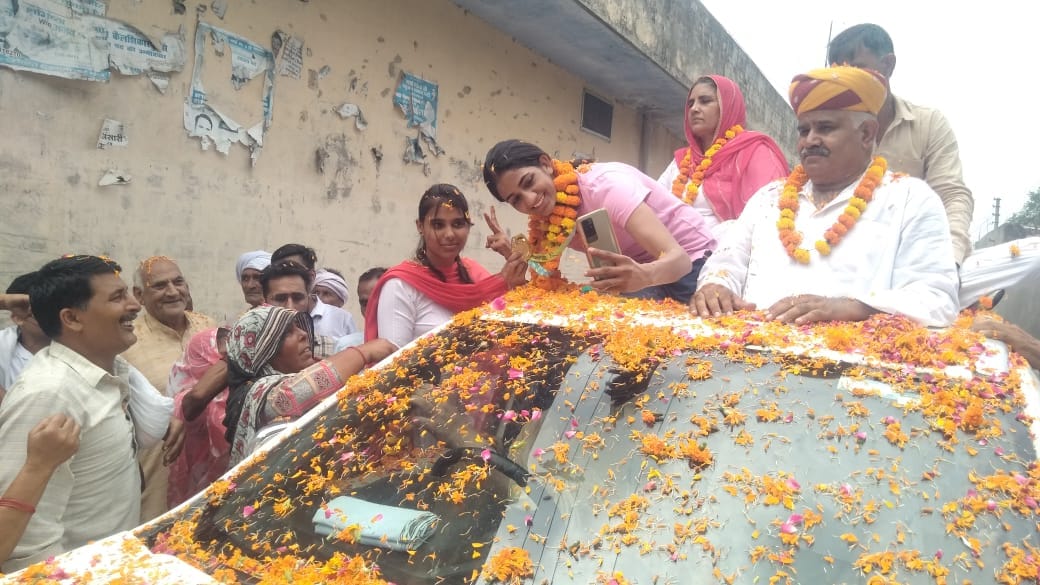 गांव कैल शिकारपुर में बॉक्सर नीतू घणघस के साथ सेल्फी लेती युवतियां।