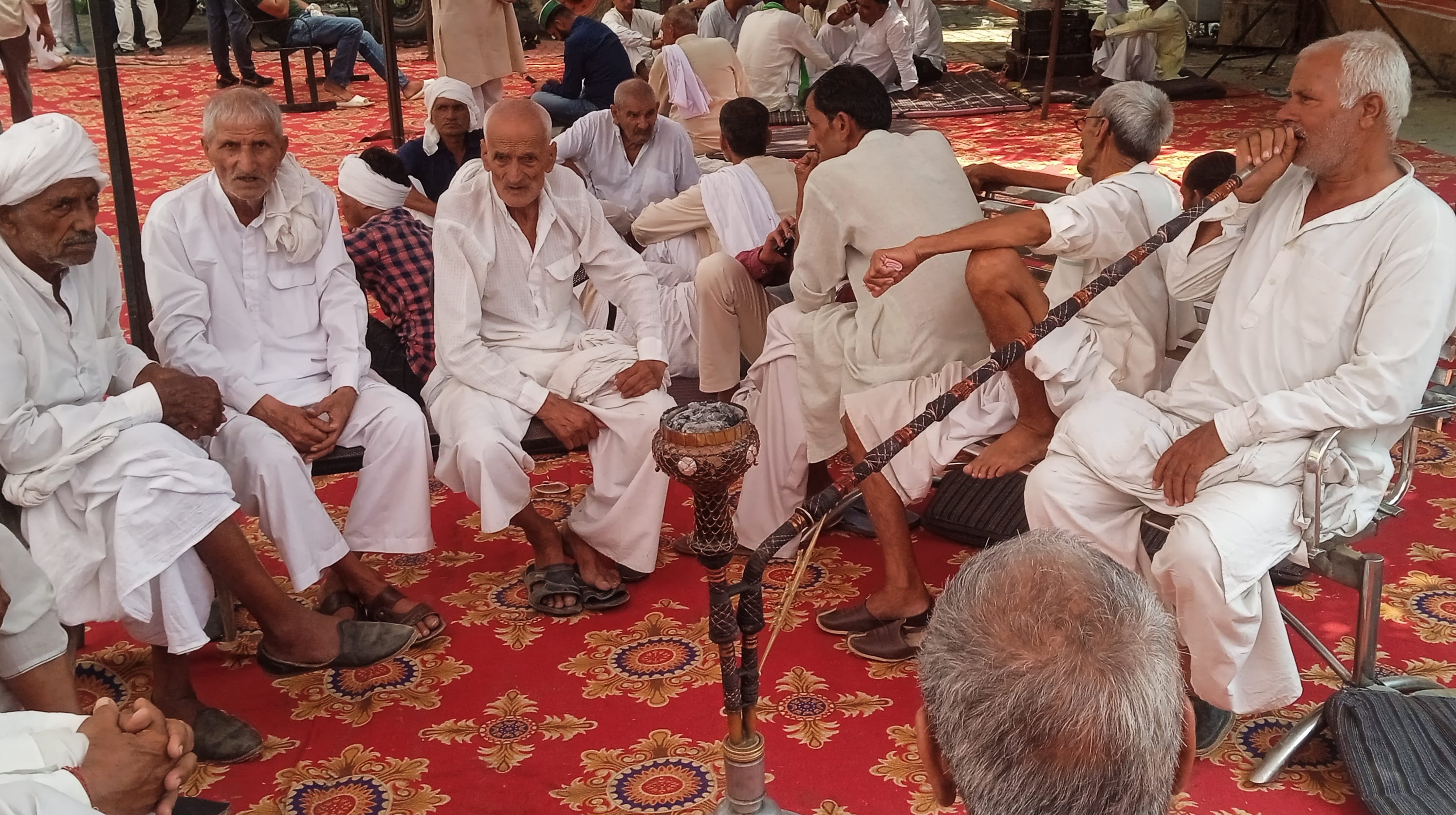 शामली कलक्ट्रेट में धरने पर आपस में चर्चा करते किसान।