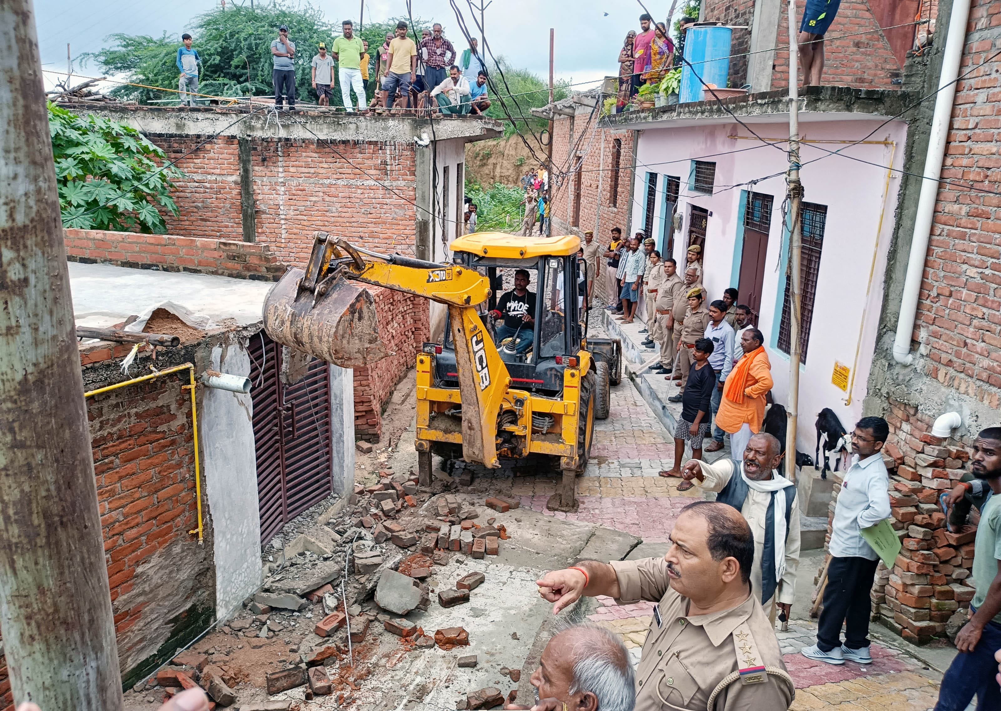 शहर के गौरादेवी नई बस्ती मोहल्ले में आरोपी के घर में अवैध निर्माण को गिराती जेसीबी मशीन। संवाद