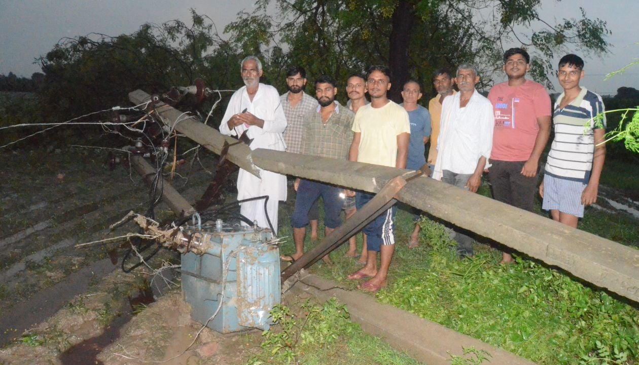 लालपुर गांव में शाम के समय तेज तूफान आने के कारण खेत में टुटे पड़े बिजली के खंभे को देखते ग्रामीण । लालपुर गांव में शाम के समय तेज तूफान आने के कारण खेत में टुटे पड़े बिजली के खंभे को देखते ग्रामीण ।