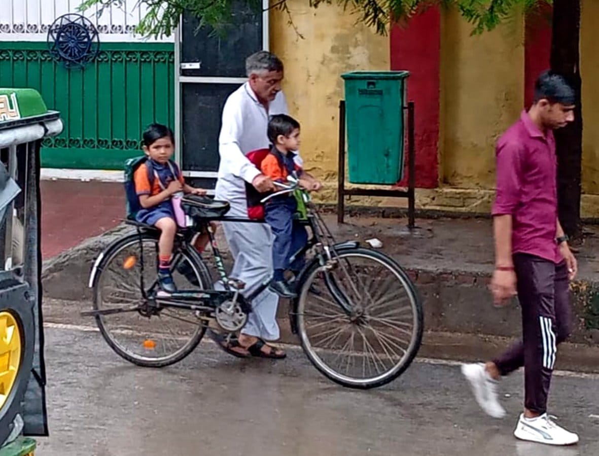 बागपत में बारिश के चलते छुट्टी पढ़ने पर सुबह बच्चों को वापस साइकिल से घर ले जाता वृद्घ