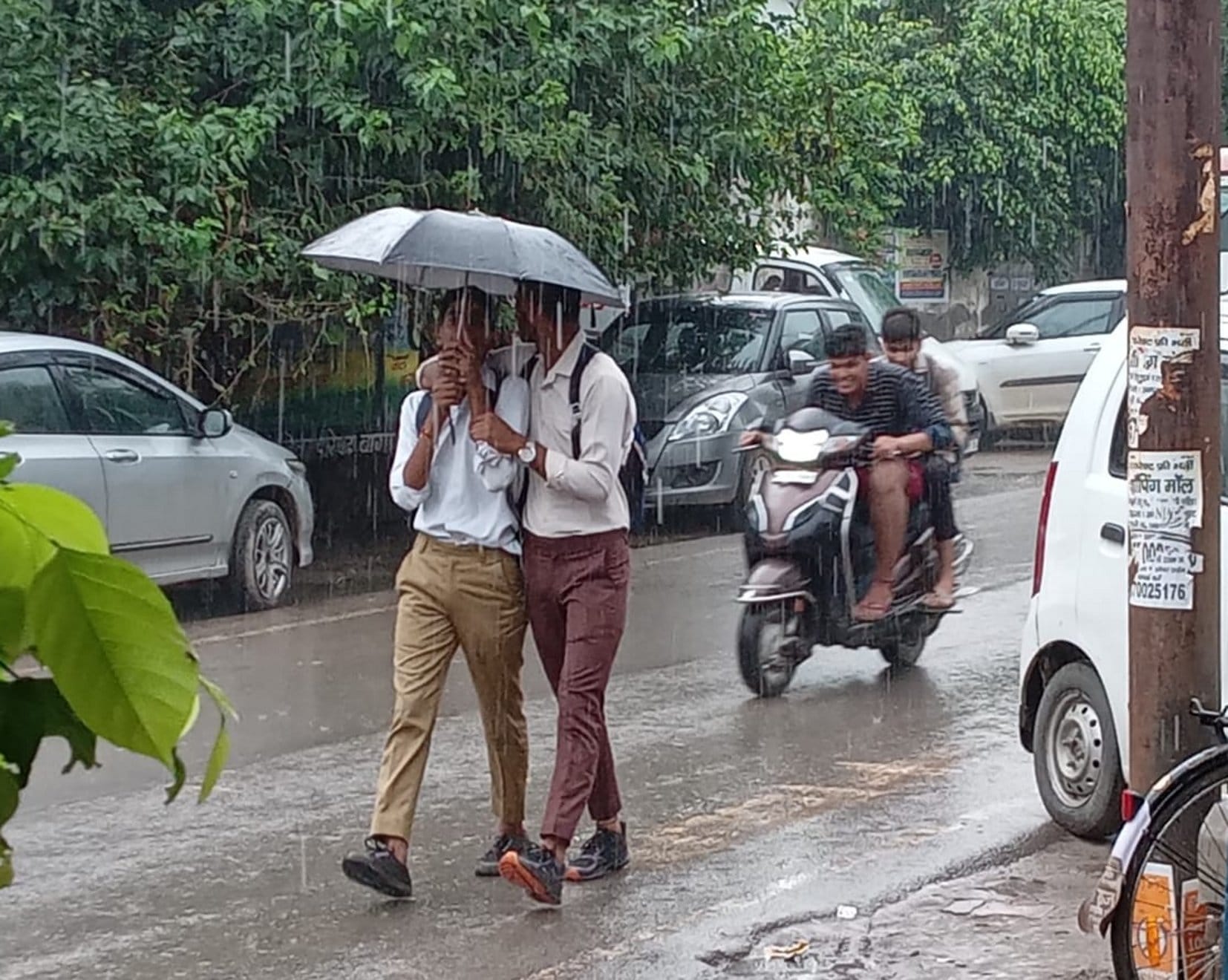 बागपत में शुक्रवार को झमाझम बारिश के बीच कालेज से आते छात्र