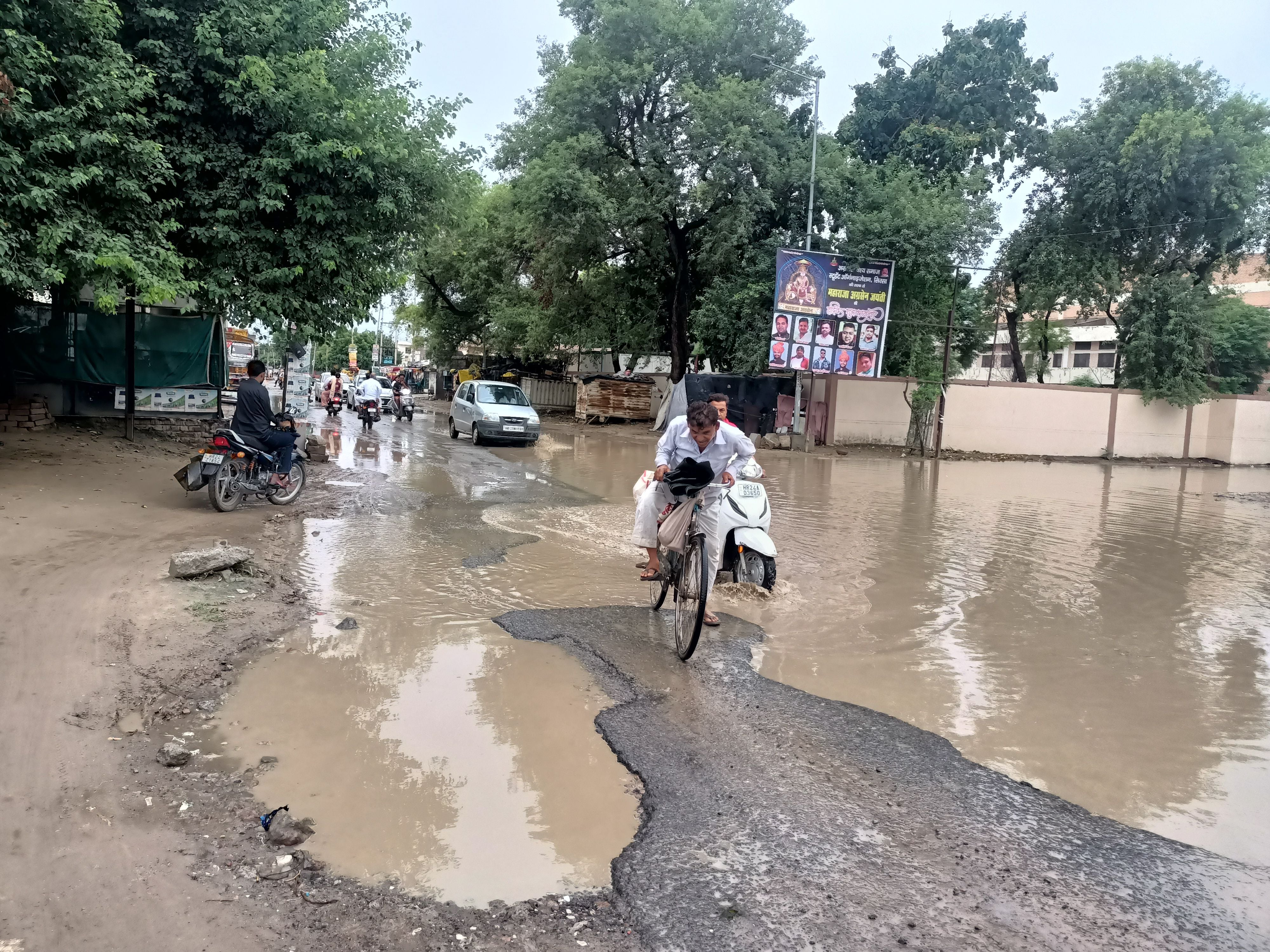 कपास मंडी के बाहर जलभराव के बीच से गुजरते वाहन चालक ।  संवाद