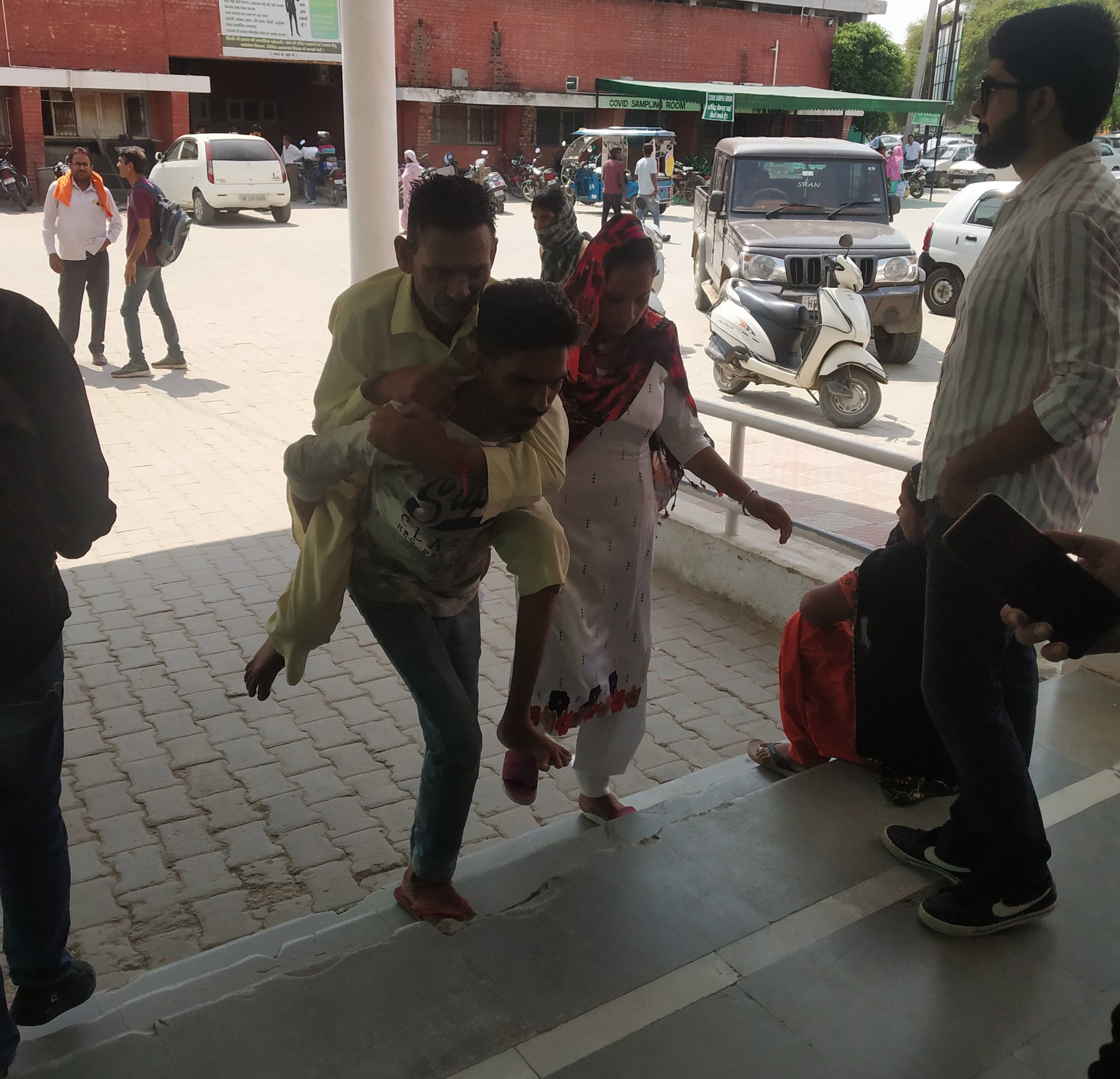 पिता के पैर खराब होने के कारण उसे कंधे पर उठाकर वार्ड में इलाज के लिए लेकर जाता बेटा ।  संवाद