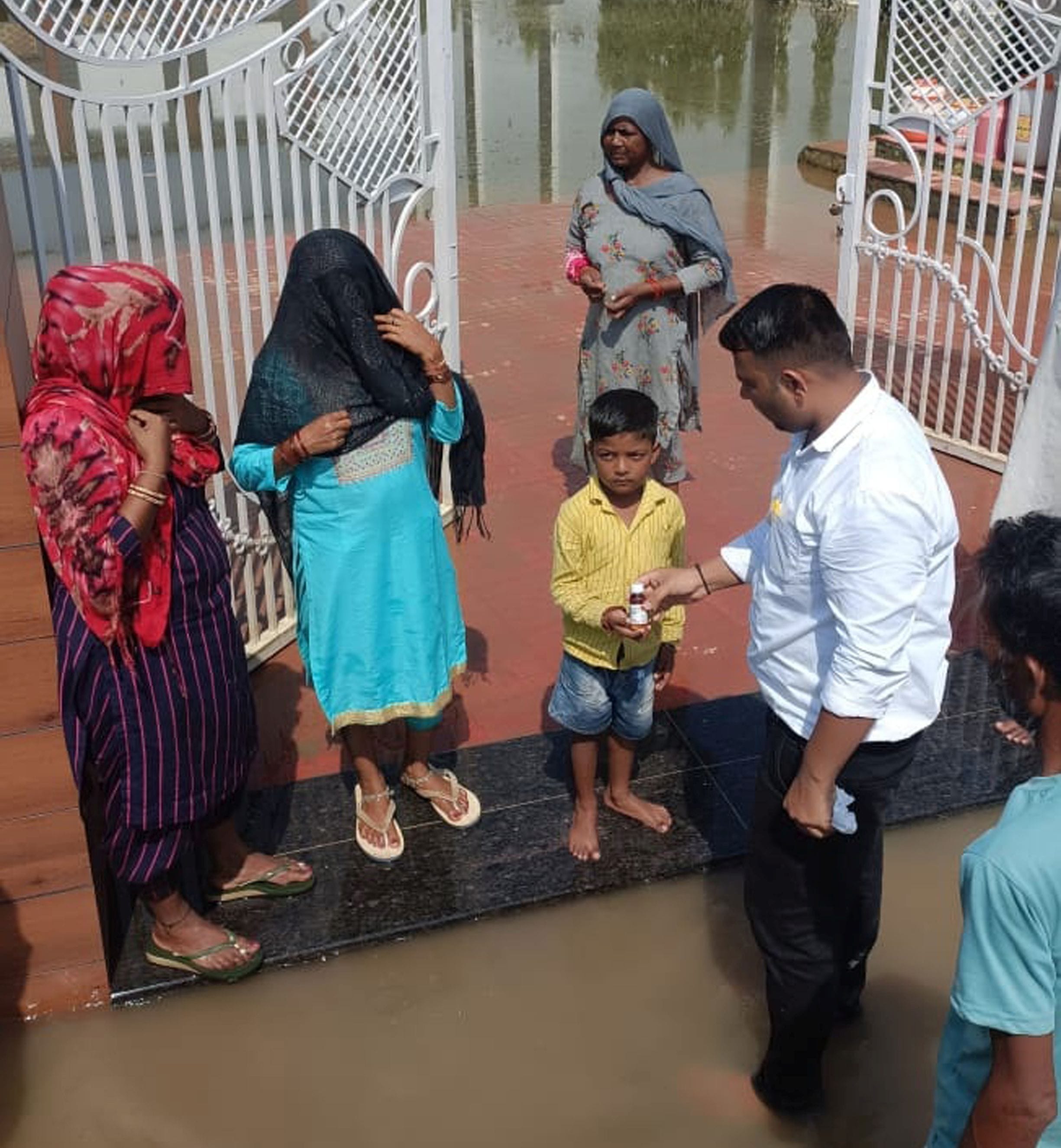 भूना में जलभराव के बीच बच्चे को दवा देने पहुंचा स्वास्थ्यकर्मी। भूना में जलभराव के बीच बच्चे को दवा देने पहुंचा स्वास्थ्यकर्मी।