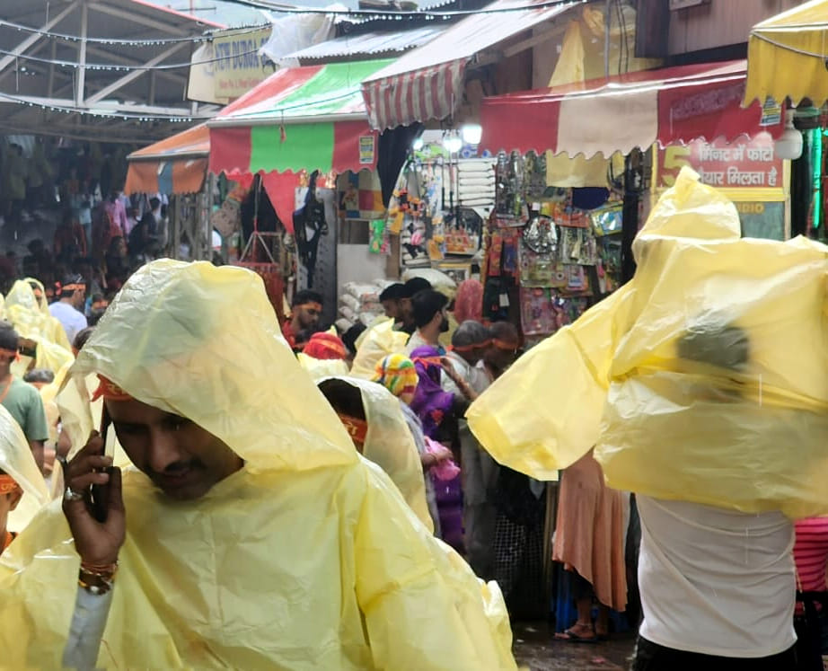 बारिश कम हाने के बाद श्रदालु दुकान से बरसाती खरीद कर भवन की और जाते हुए बारिश कम हाने के बाद श्रदालु दुकान से बरसाती खरीद कर भवन की और जाते हुए