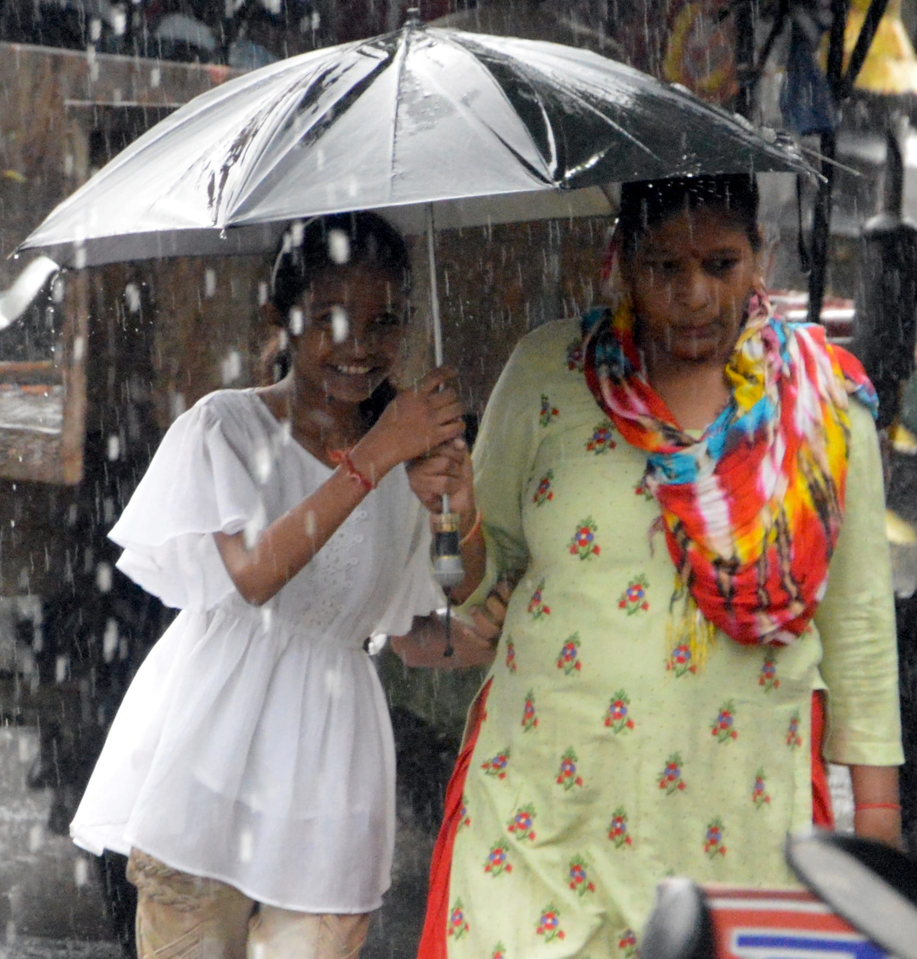 बिजनौर में मंगलवार को हुई बारिश में छाता लगाकर जाती महिला और युवती।