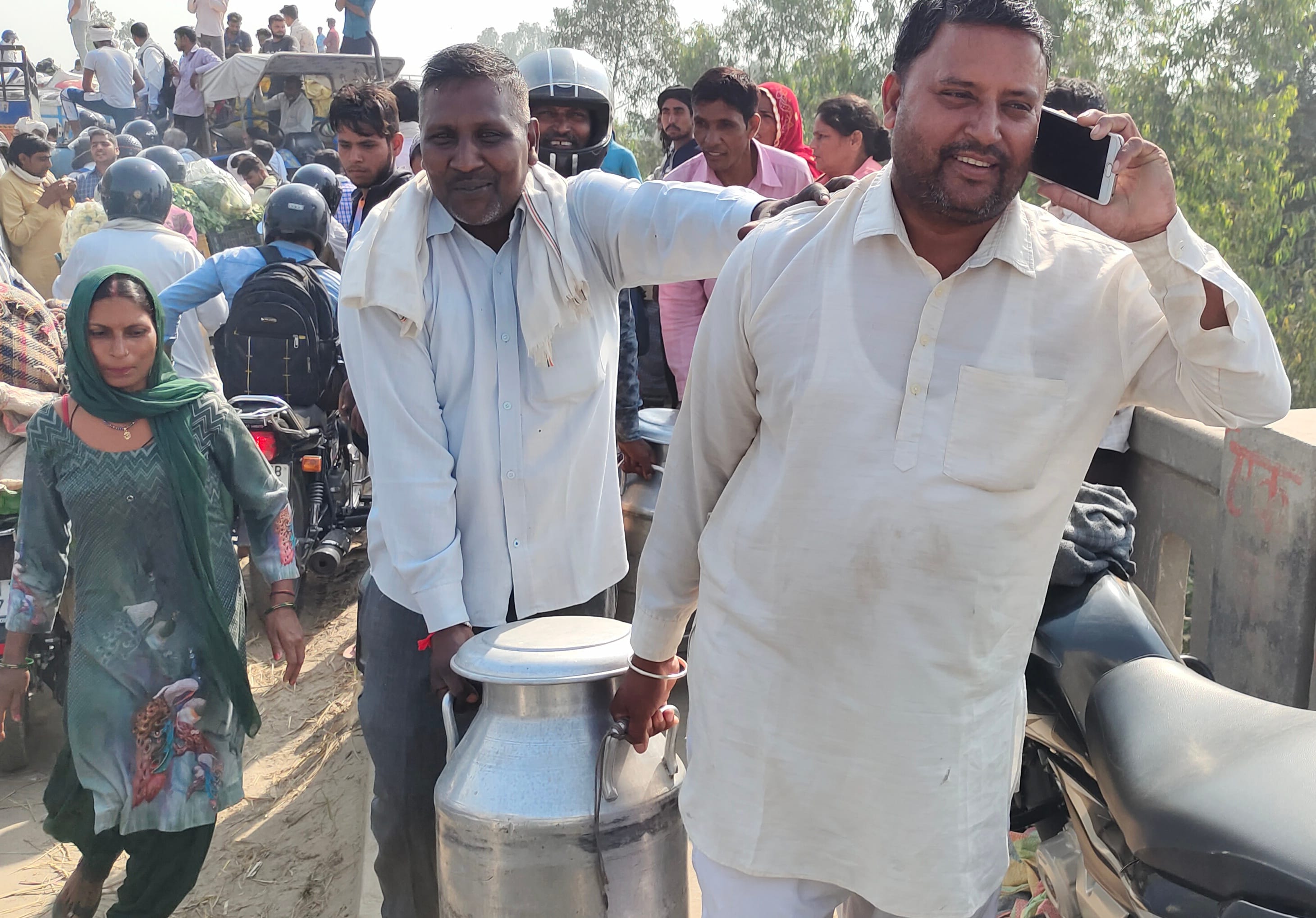 वाहन से दूध की कैन नीचे उतारकर पैदल ले जाते दूधिया। वाहन से दूध की कैन नीचे उतारकर पैदल ले जाते दूधिया।