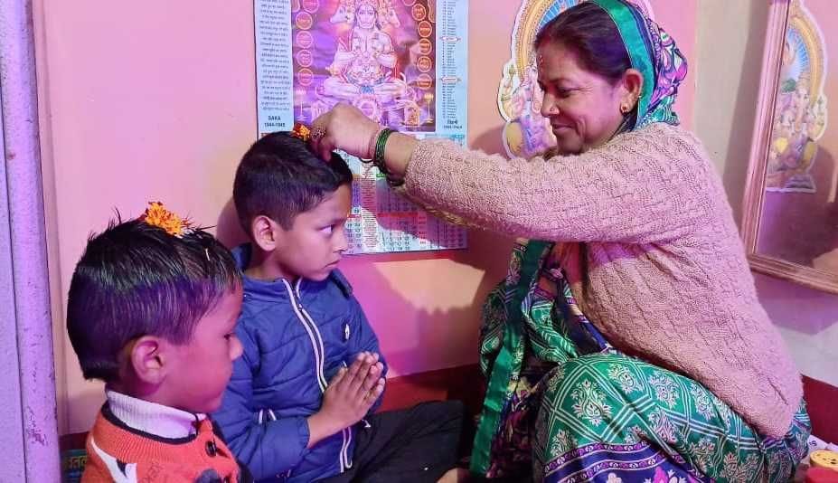बागेश्वर के नदीगांव में बच्चों के मस्तक पर च्यूड़े रखती महिला। संवाद बागेश्वर के नदीगांव में बच्चों के मस्तक पर च्यूड़े रखती महिला। संवाद