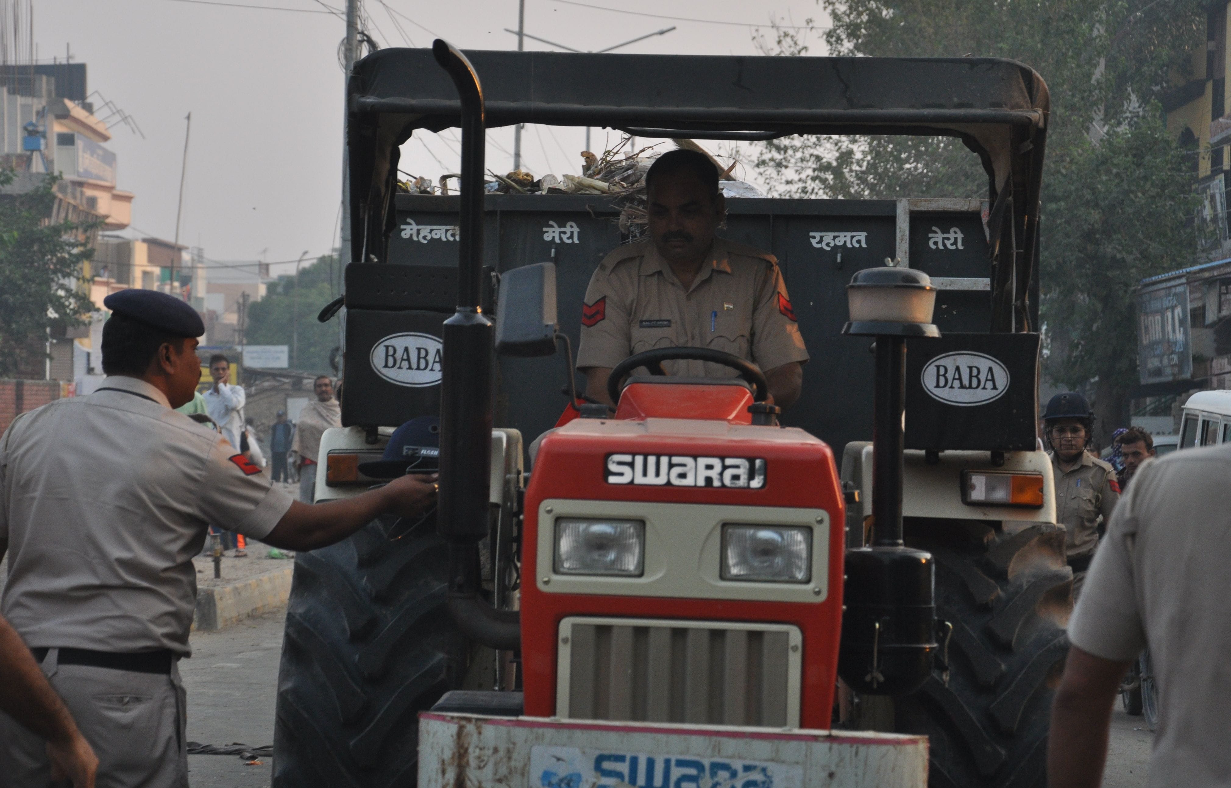 हिसार कचरे की ट्राली के ड्राइवर के चोट लगने के बाद पुलिसकर्मी ट्रैक्टर ट्रॉली ले जाता हुआ। संवाद