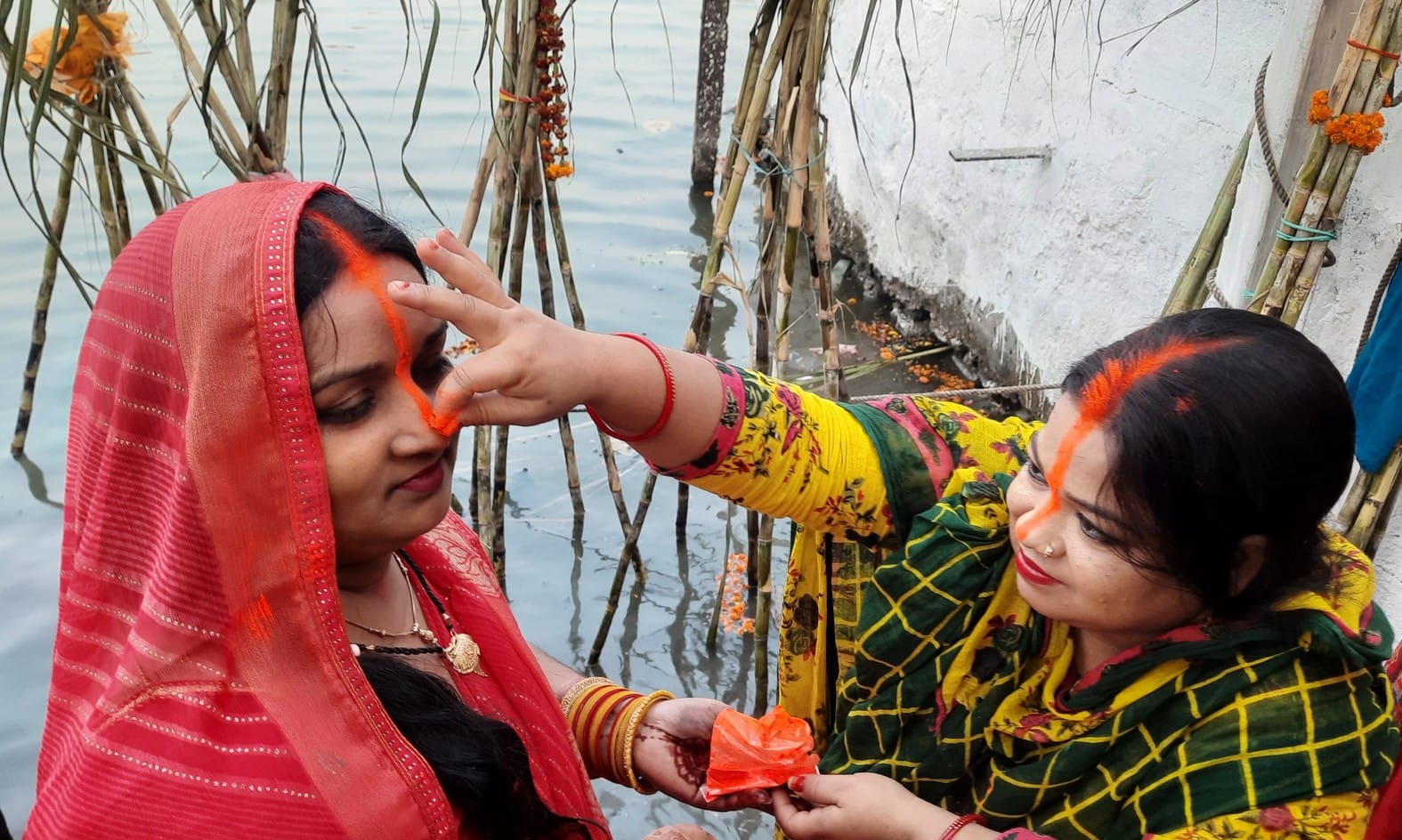 बलुआ में छठ व्रती को सिंदूर लगाती महिला। संवाद बलुआ में छठ व्रती को सिंदूर लगाती महिला। संवाद
