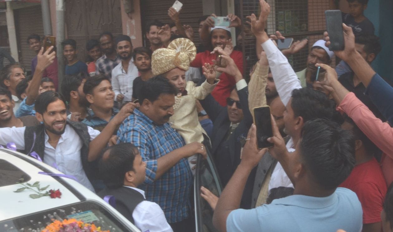 हापुड़। कार से उतरकर लोगों का अभिवादन करते दूल्हा अजीम। संवाद