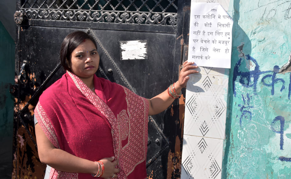 आशीर्वाद कॉलोनी में अपने घर के बाहर मकान बेचने के लिए लगाया गया पर्चा दिखाती महिला। आशीर्वाद कॉलोनी में अपने घर के बाहर मकान बेचने के लिए लगाया गया पर्चा दिखाती महिला।
