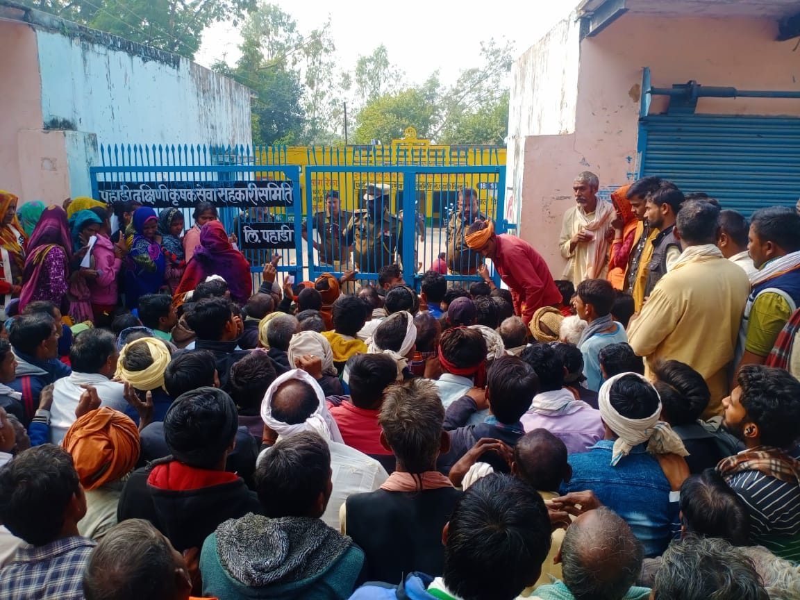 फोटो-12- पहाड़ी में सहकारी समिति का गेट बंद कर टोकन के हिसाब से खाद बंटवाती पुलिस। संवाद