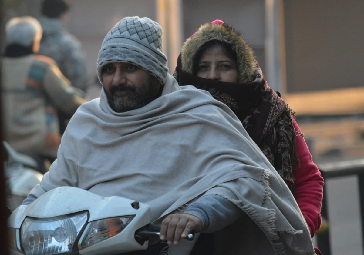 सुबह ठंड से बचाव के लिए ऊनी कपडों में जाते वाहन सवार।