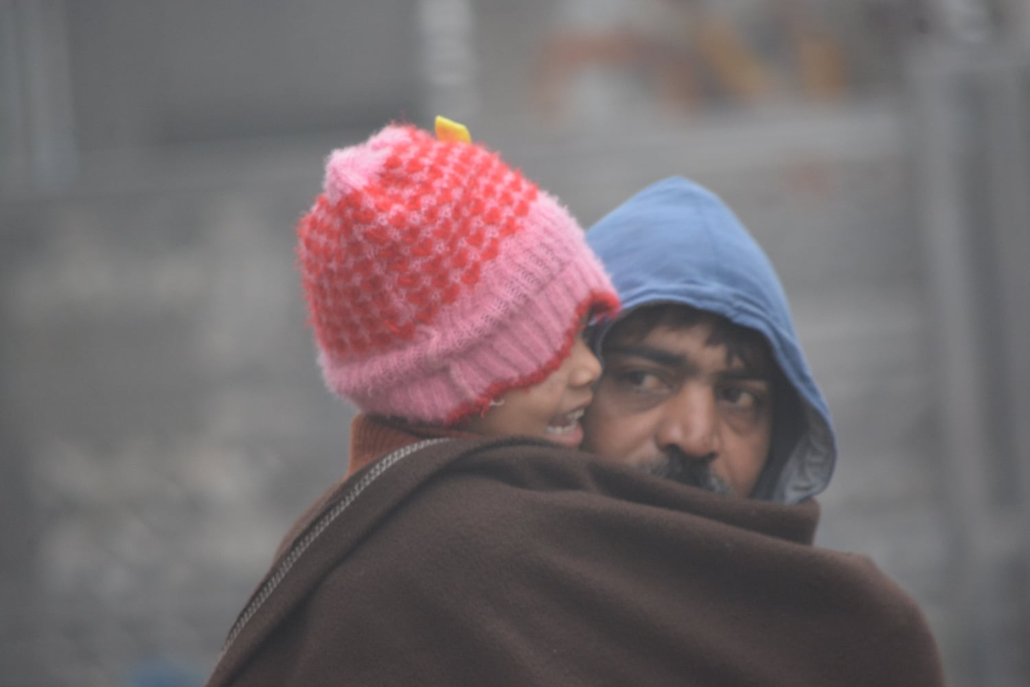 बच्चें को ऊनी कपडों में लपेटकर ठंड व कोहरे से बचाव करता युवक। बच्चें को ऊनी कपडों में लपेटकर ठंड व कोहरे से बचाव करता युवक।