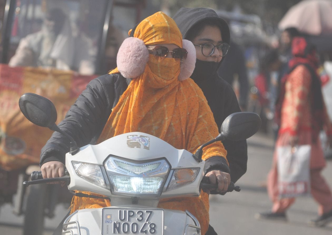 तेज हवा से बचने के लिये कानों पर इयर मफ्स लगाकर स्कूटी चलाती युवती । संवाद तेज हवा से बचने के लिये कानों पर इयर मफ्स लगाकर स्कूटी चलाती युवती । संवाद