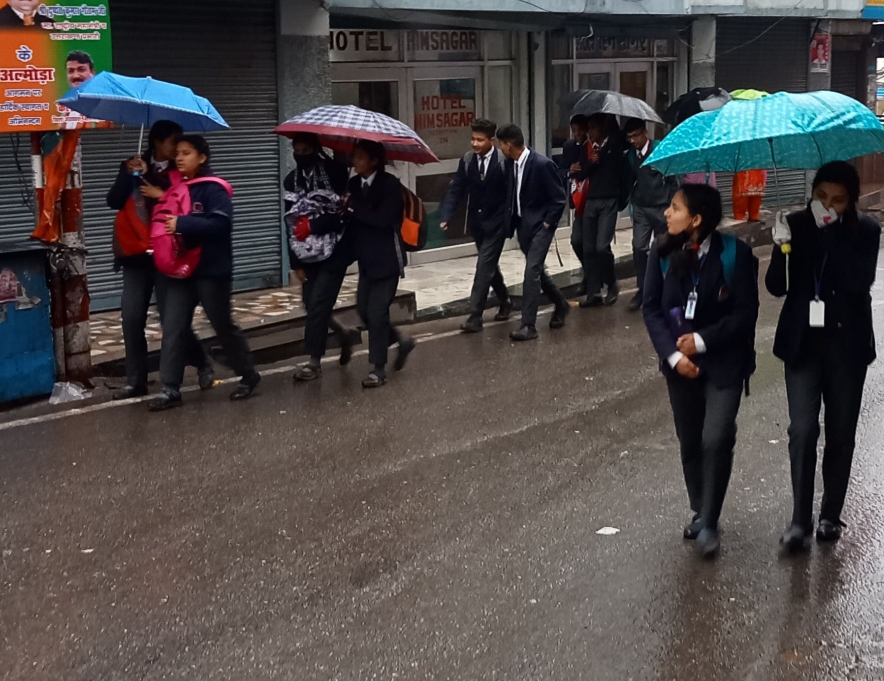 अल्मोड़ा में बारिश के बाद छाता के सहारे स्कूल से आते बच्चे।संवाद