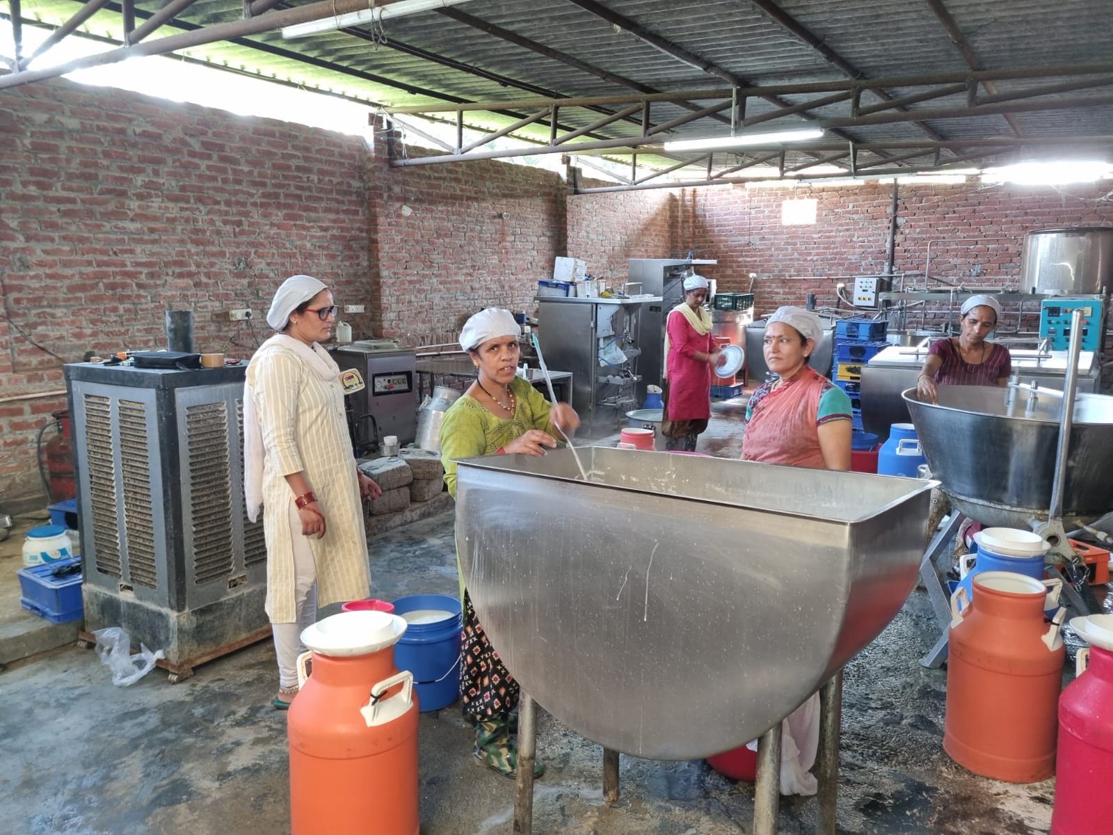 दूध डेयरी में उत्पाद तैयार करती महिला कर्मचारी। संवाद दूध डेयरी में उत्पाद तैयार करती महिला कर्मचारी। संवाद
