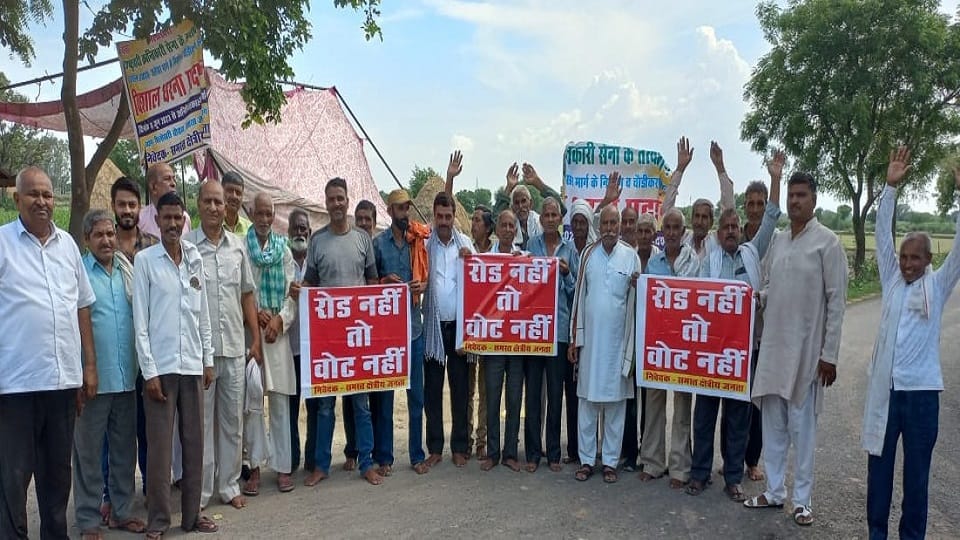 सड़क निर्माण के लिए रोड नहीं तो वोट नहीं के पोस्टर लेकर प्रदर्शन