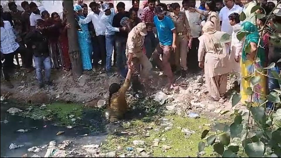 महिला को नाले से निकालती पुलिस