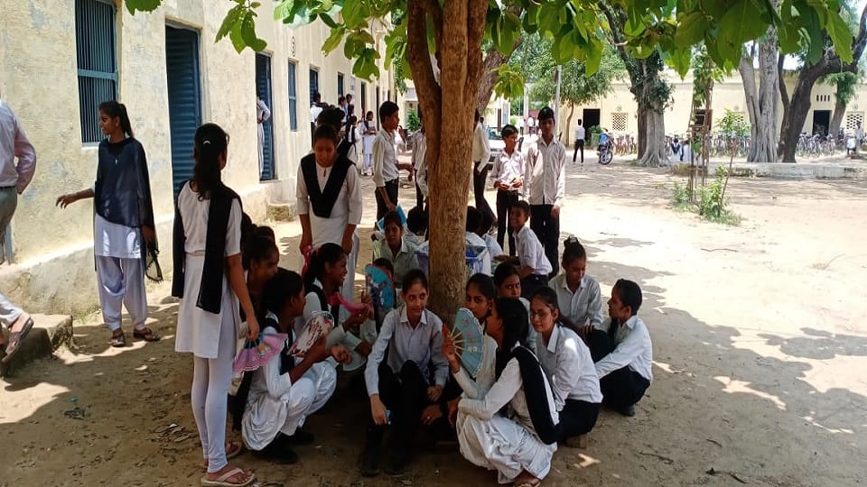 गर्मी एवं उमस के कारण पेड़ के नीचे बेठीं एमएल इण्टर कॉलेज की छात्राएं