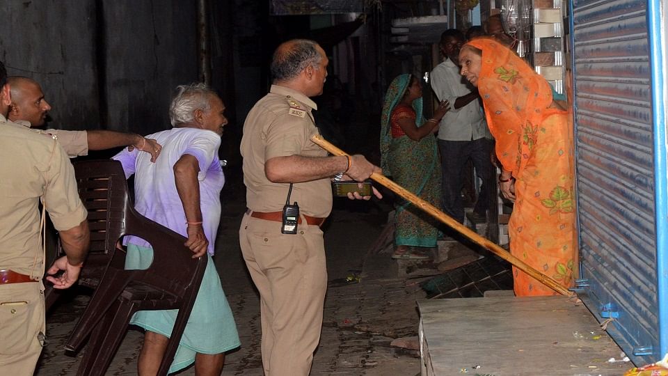 चंदनिया में गांजे को लेकर हुए पथराव के बाद घर के बाहर बैठी महिला को लाठी फटकार कर हटाते इस्पेक्टर