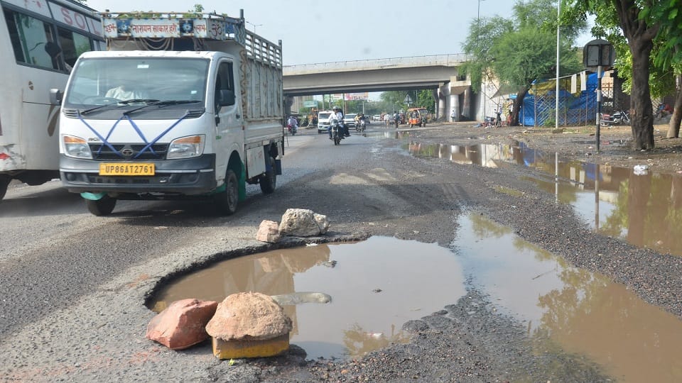 आगरा रोड पर हो रहे गड्ढों से बचकर निकलते वाहन सवार