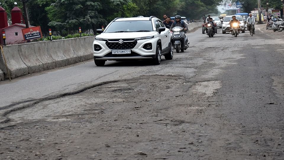 रामघाट रोड पीएसी के पास टूटी सड़क पर होकर गुजरते वाहन