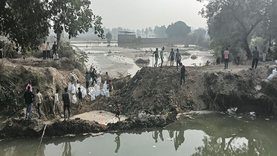 अलीगड़ रोड स्थित गांव चिंतापुर पर कटी नहरी पटरी को दुरुस्त करते ग्रामीण