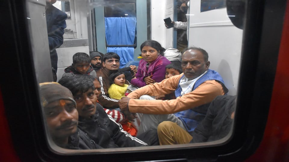 जमीन पर बैठे यात्री