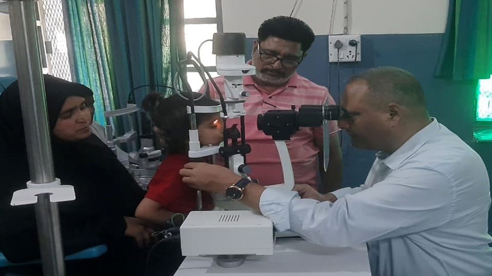 गांधी नेत्र चिकित्सालय में बच्ची की आंखों की जांच करते डॉ. अजय कुमार सक्सेना