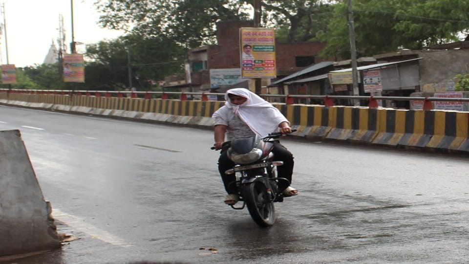 बूंदाबांदी में अलीगढ रोड पर गमछा आढ़कर जाता बाइक सवार