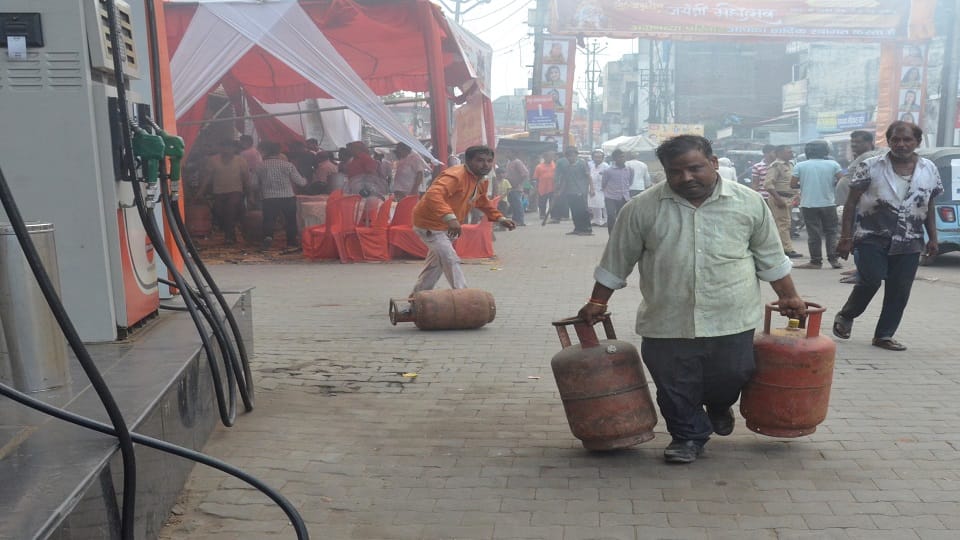 घर में रखे सिलिंडरों को ले जाते कर्मचारी