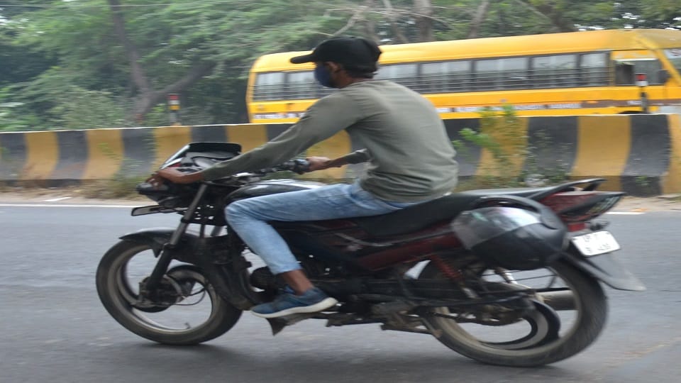 रामघाट रोड पर  हेलमेट बाइक में टांगकर लेकर जाता बाइक सवार