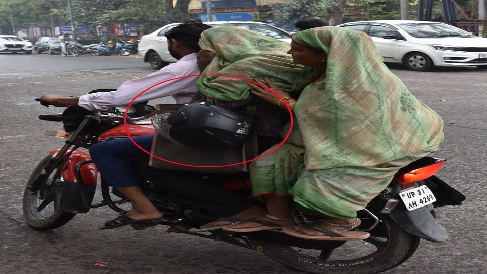 सेन्टर प्वाइंट रोड पर बाइक पर सवार तीन लोगा हाथ में हेलमेट