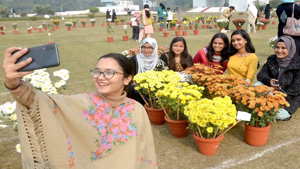 एएमयू के गुलिस्तान ए सैयद पार्क में पुष्प प्रदर्शनी में फूलों के साथ सैल्फी लेती युवतियां
