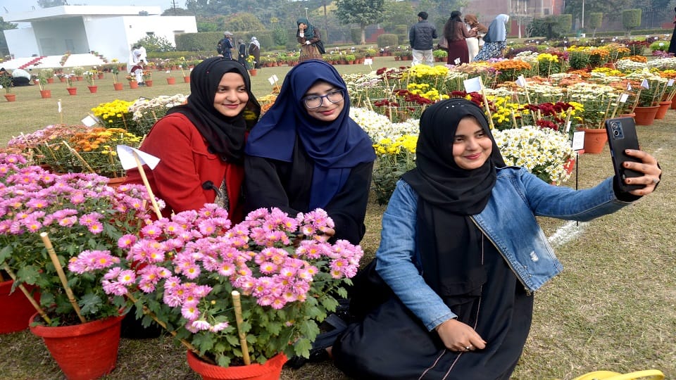 एएमयू के गुलिस्तान ए सैयद पार्क में पुष्प प्रदर्शनी में फूलों के साथ सैल्फी लेती युवतियां
