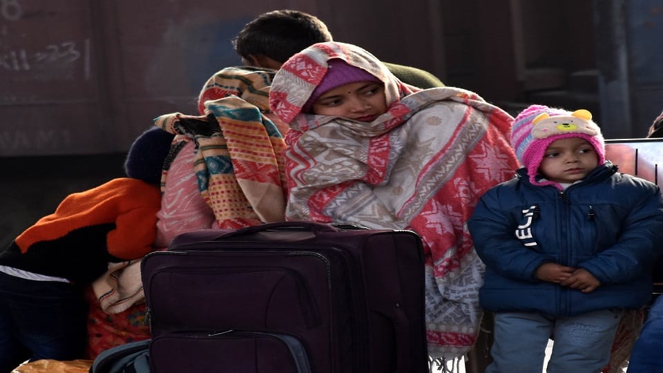 रेलवे स्टेशन पर ठंड में शॉल ओढकर कर बैठी महिला ट्रेन का इंतजार करती