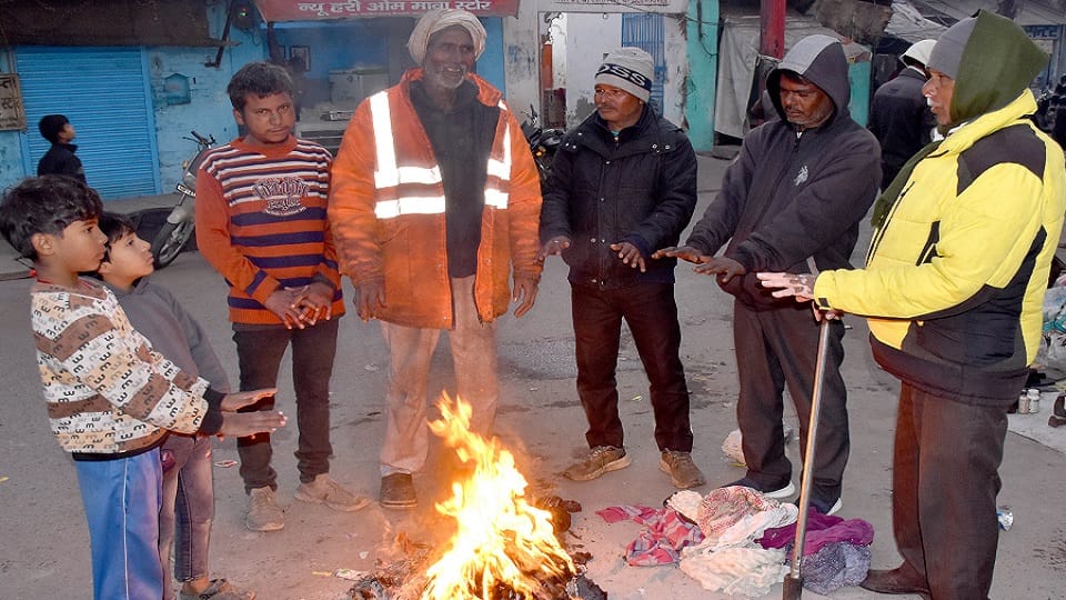 अचल ताल पर ठंड में कपड़ा जलाकर लाव पर हाथ सेंकते लोग