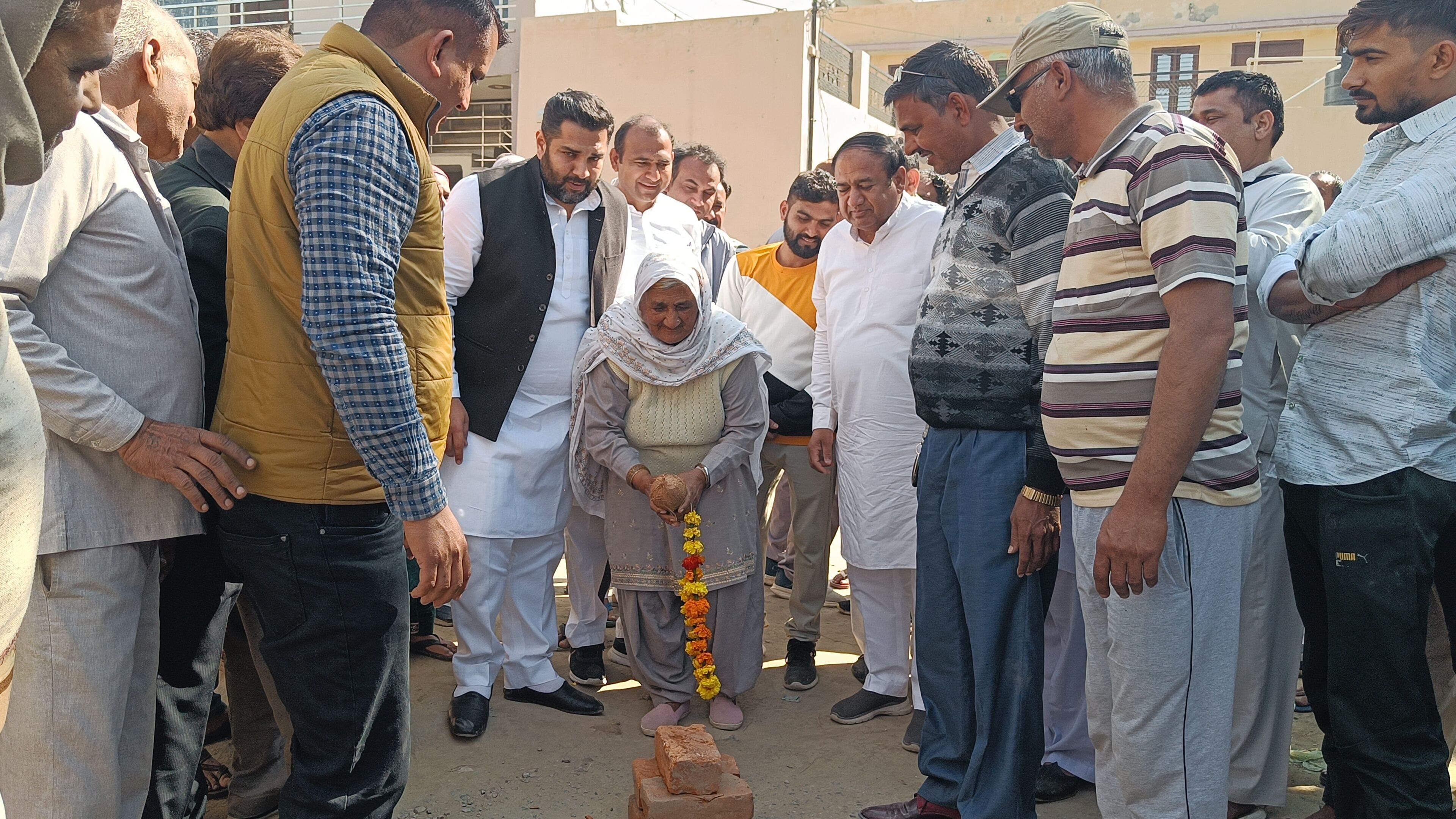 फोटो 07: गढ़ शहजानपुर में बुजुर्ग रामरती से नारियल तुड़वाकर विकास कार्य शुरू कराते मेयर निखिल मद
