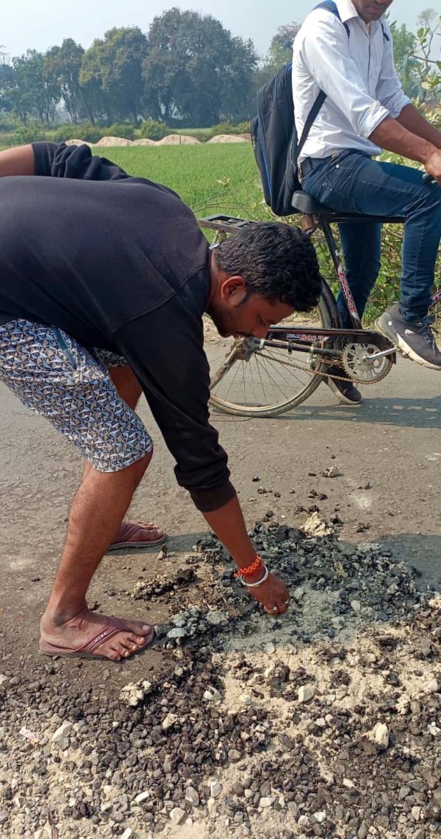 खुटार रसवां कलां मार्ग की हाथ से कोलतार गिट्टी हटाकर दिखाता बुजुर्ग। संवाद खुटार रसवां कलां मार्ग की हाथ से कोलतार गिट्टी हटाकर दिखाता बुजुर्ग। संवाद