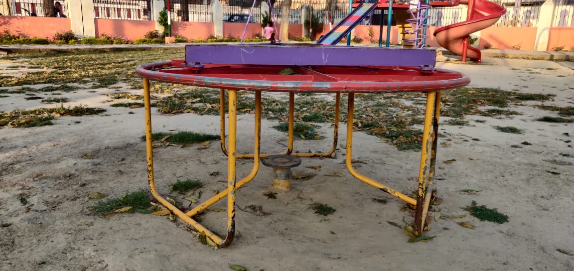 गांधी पार्क में एक साइट से टूटे झूले पर बैठा बच्चा