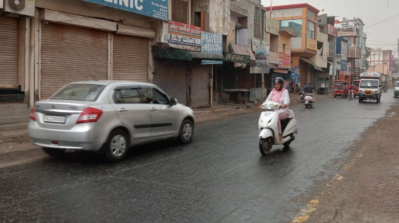 फोटो 46- बूंदाबांदी के बीच स्कूटी पर सवार होकर जाती महिला। संवाद