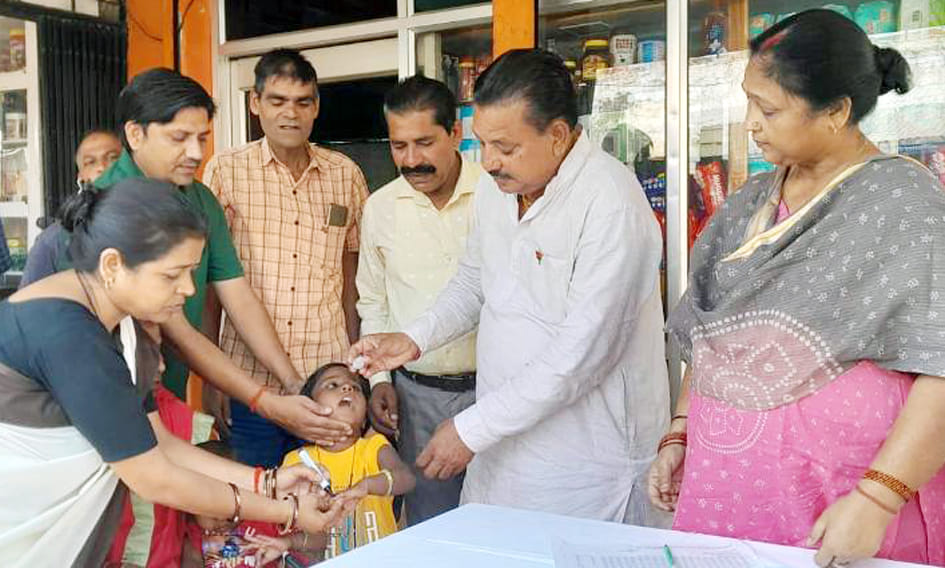 बच्चे को पोलियो ड्राप पिलाते जिला प्रतिरक्षण अधिकारी