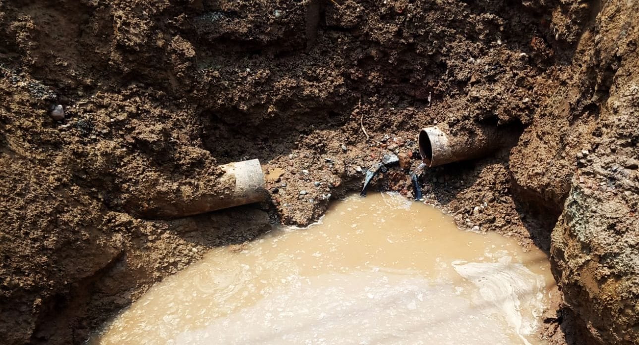 लाल इमली चौराहा पर सड़क की खोदाई के दौरान उड़ती धूल और मुंह ढककर निकलती युवतियां