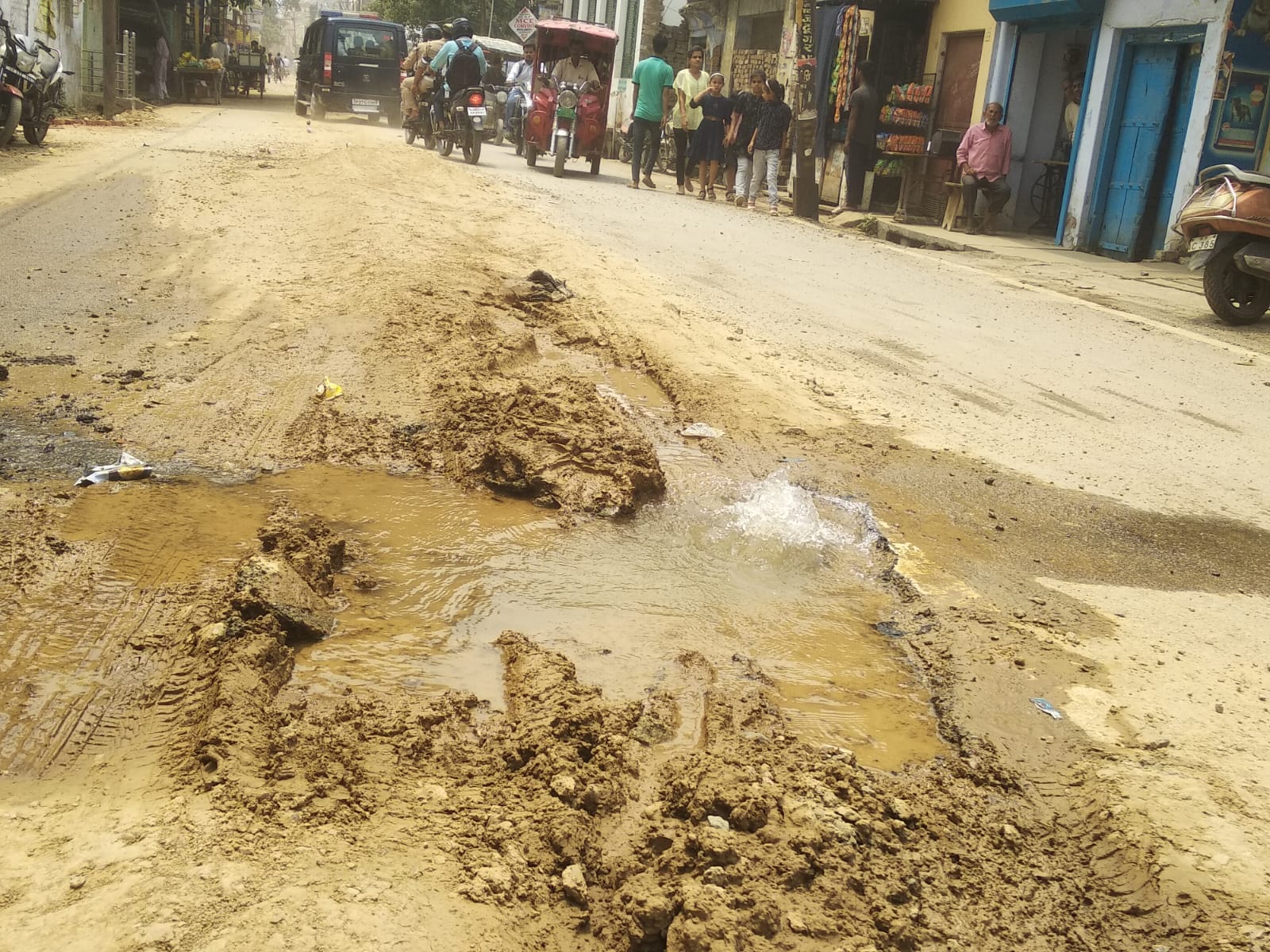 लाल इमली चौराहा पर सड़क की खोदाई के दौरान उड़ती धूल और मुंह ढककर निकलती युवतियां