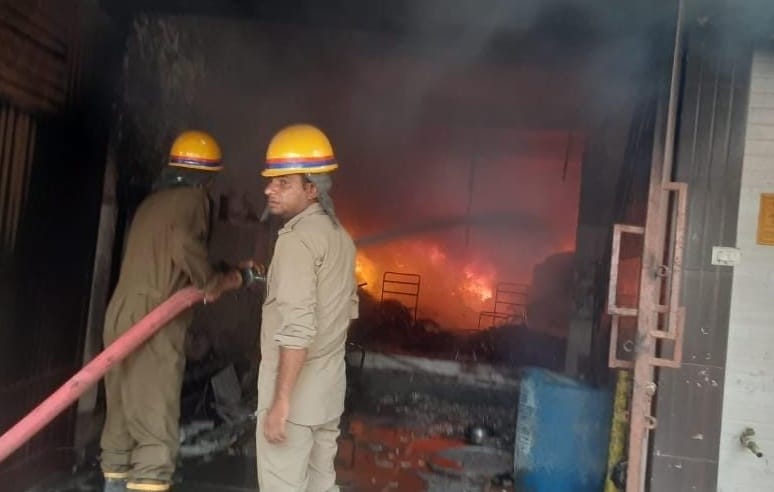 लोनी। लाल बाग कॉलोनी स्थित टेंट की दुकान में लगी आग को बुझाते लोग।