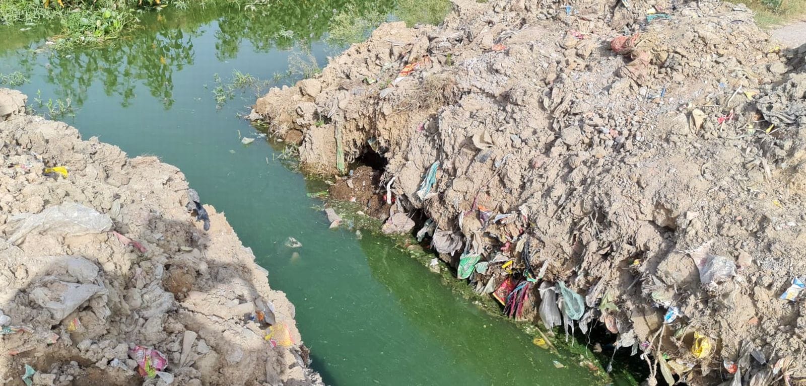 ग्राम पनौटा के मुख्य मार्ग पर पुलिया बनाने को खोदी गई सड़क और उससे निकलते बच्चे। संवाद