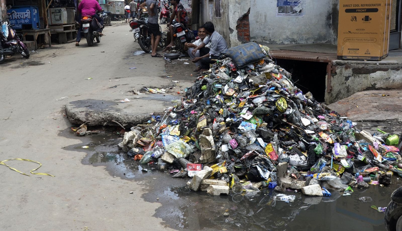 सुपर मार्केट के पास सड़क पर फैली गंदगी से बचकर निकलते लोग। संवाद